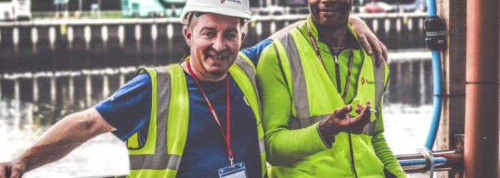 selective focus photography of two men standing side by side wearing green reflective vests